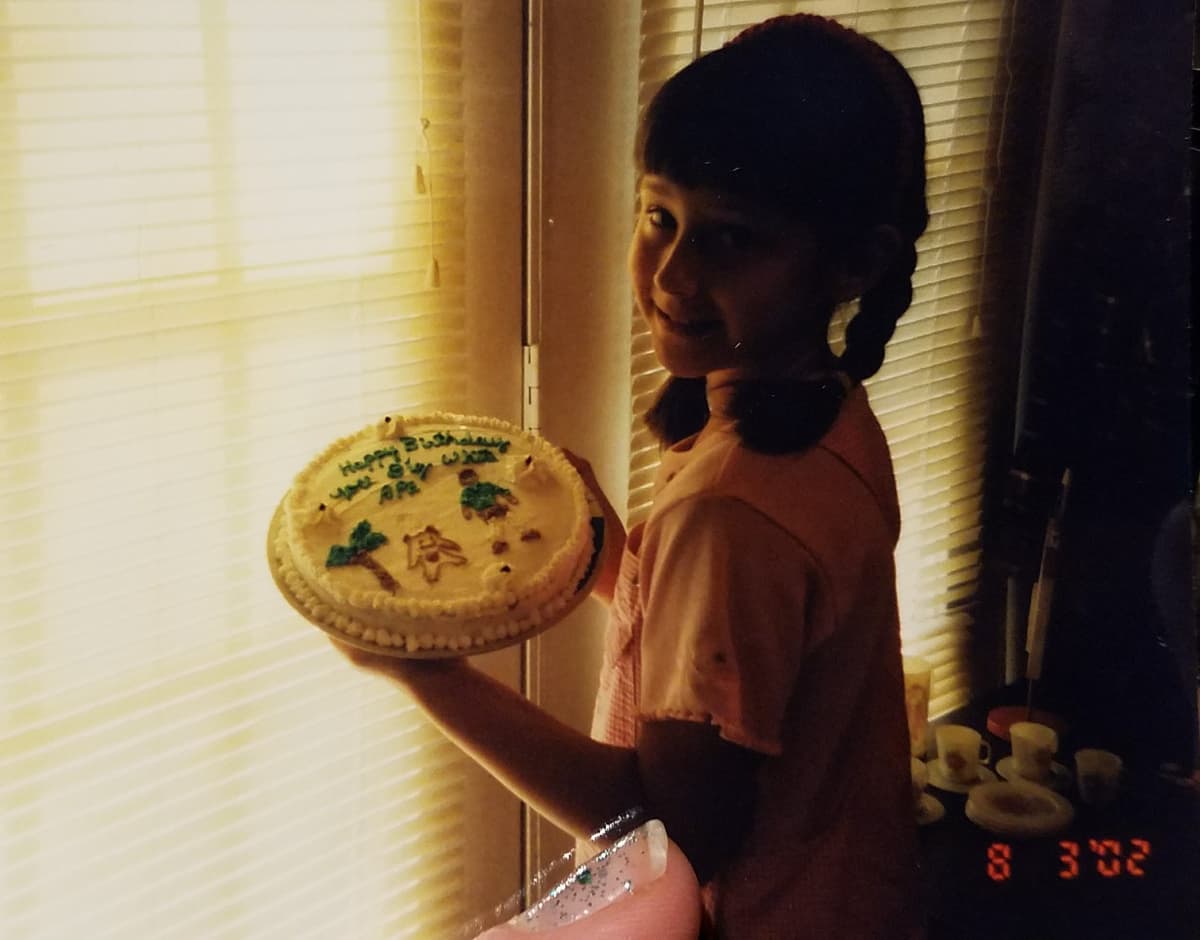 girl in pink shirt holding brothers birthday cake