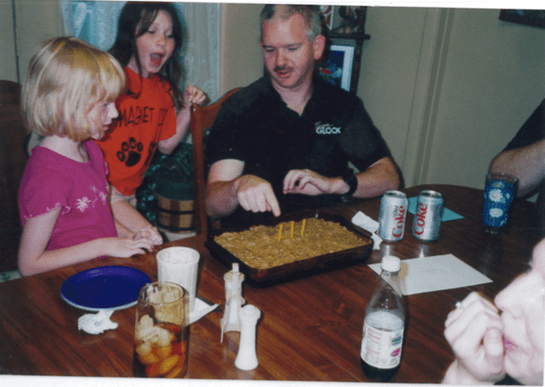 two small girls bery excited to help dad with candles on cake